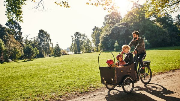 Språknivåer. Familj cyklar i park.