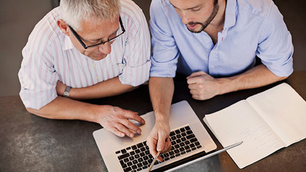 Two men in shirts workning on a laptop, reading the terms of registration