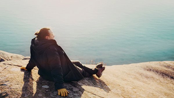 En person på klippor tittar ut över havet - här hittar du företagsutbildningar på Folkuniversitetet Gotland