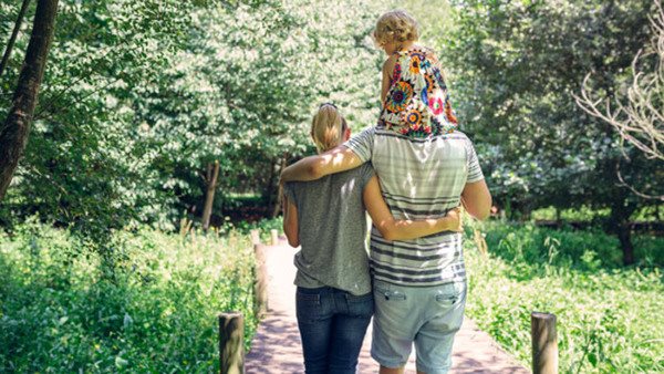 Spain, Asturias, Unrecognizable family with baby girl walking on a wooden walkway in the countryside