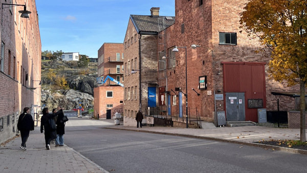 Några människor som går längs en gata bredvid höga byggnader.