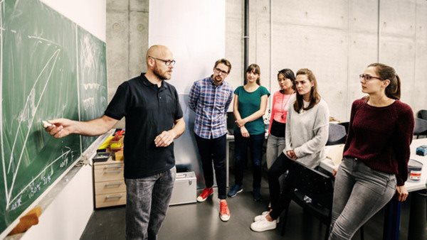 A group of university students attending a lab work seminar with their technician.