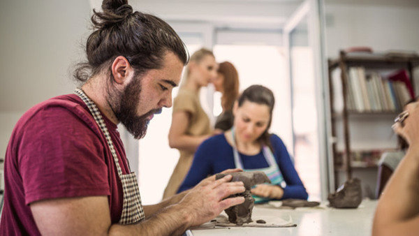 Group of people learning ceramic art. They are modeling clay for making ceramic works