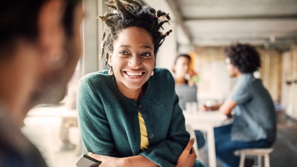 Smiling businesswoman sitting with male colleague at table in office cafeteria