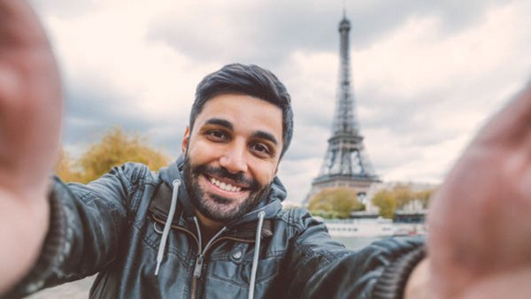 Man tar en selfie framför Eiffeltornet