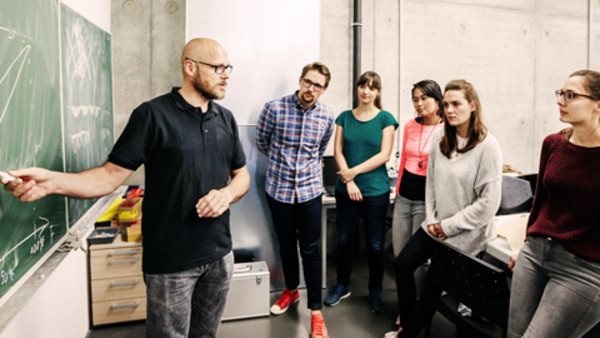 A group of university students attending a lab work seminar with their technician.